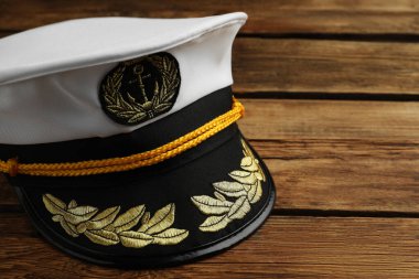 Peaked cap with accessories on wooden background, closeup. Space for text