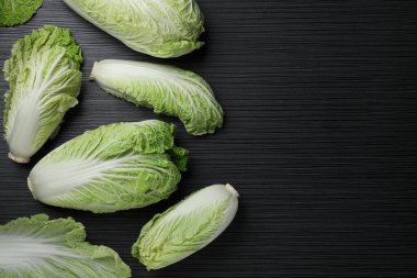 Fresh ripe Chinese cabbages on black wooden table, fat lay. Space for text
