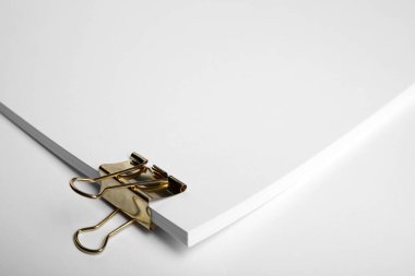 Sheets of paper with clip on white background, closeup