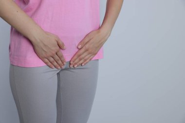 Woman suffering from herpes genital on grey background, closeup. Space for text