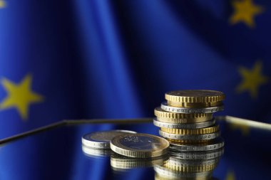 Coins on table against European Union flag, space for text