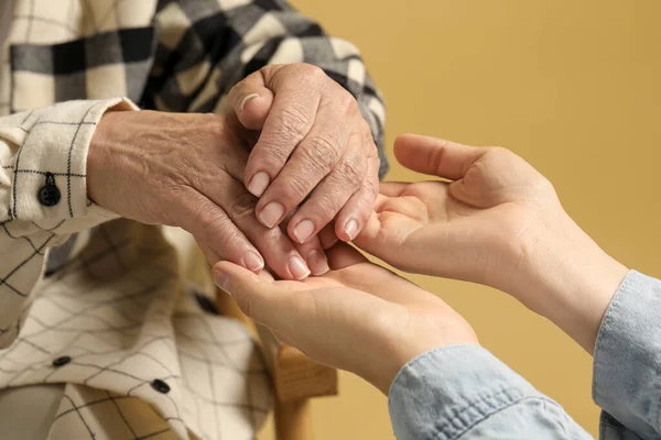 Young Elderly Women Holding Hands Beige Background Closeup — Zdjęcie stockowe
