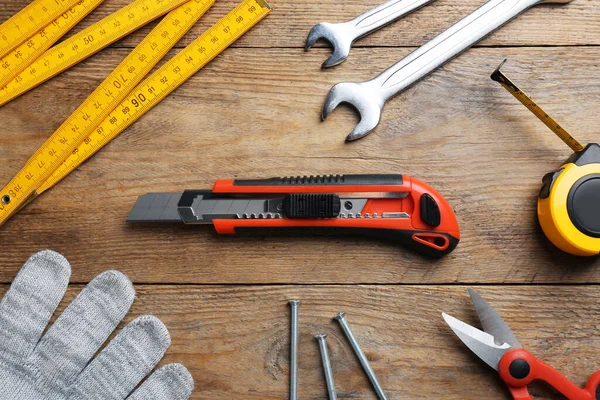 Flat lay composition with utility knife and different tools on wooden table