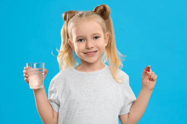 Niña Con Píldora Vitamínica Vaso Agua Sobre Fondo Azul —  Fotos de Stock