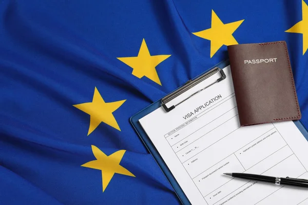 Visa application form, passport and pen on flag of European Union, flat lay. Space for text