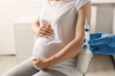 Doctor giving injection to pregnant woman in hospital, closeup