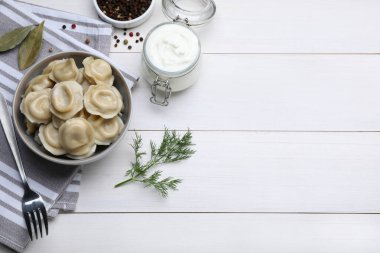 Delicious dumplings served on white wooden table, flat lay. Space for text