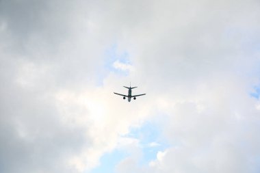 Modern white airplane flying in cloudy sky, low angle view