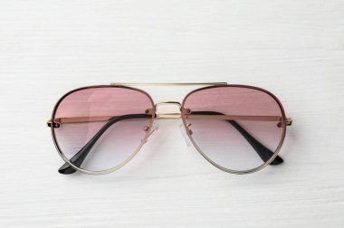New stylish sunglasses on white wooden table, top view