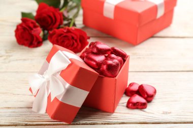 Heart shaped chocolate candies in box on white wooden table. Valentine's day celebration