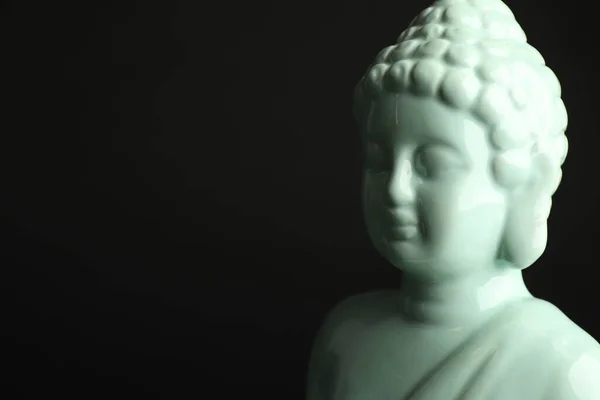 Beautiful ceramic Buddha sculpture on black background. Space for text