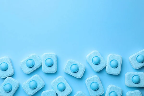 Water softener tablets on light blue background, flat lay. Space for text