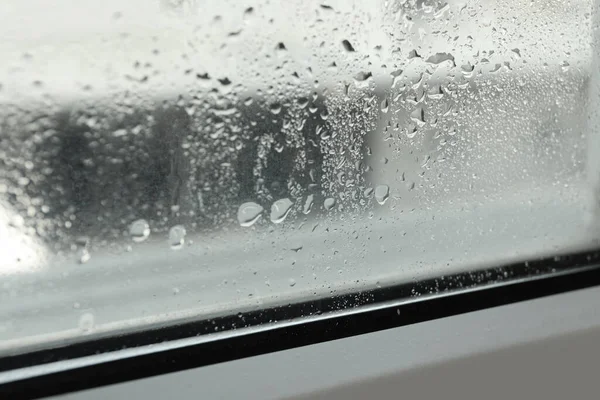 Window glass with drops of condensate indoors, closeup