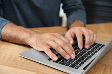 Ahşap masada dizüstü bilgisayar kullanan adam, yakın plan.