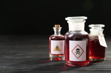 Bottles with poison on black wooden table. Space for text