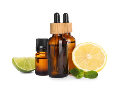 Bottles of different citrus essential oils and fresh fruits on white background