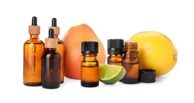 Bottles of different citrus essential oils and fresh fruits on white background