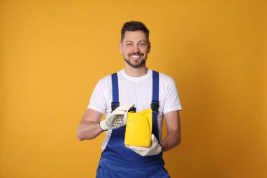 Man holding yellow container of motor oil on orange background