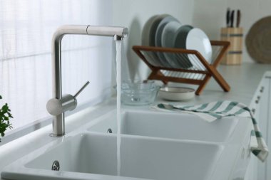 Stream of water flowing from tap in kitchen, space for text