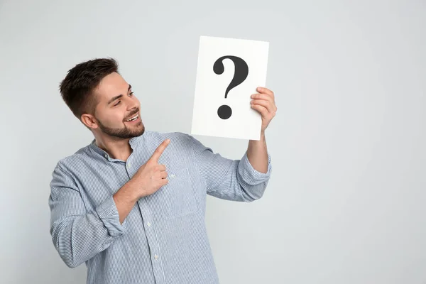 Happy Man Holding Question Mark Sign Light Background — Stock fotografie