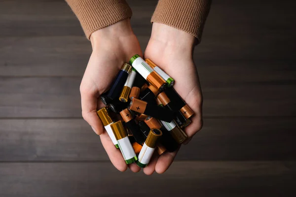 Woman Holding Many Used Electric Batteries Her Hands Wooden Table — Stock fotografie