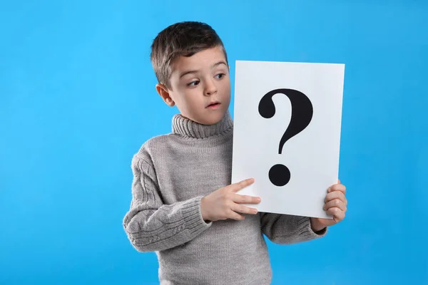 Emotional Little Boy Holding Paper Question Mark Light Blue Background — ストック写真