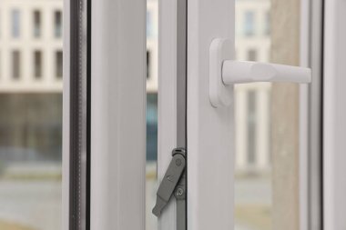 Open window with white plastic frame indoors, closeup