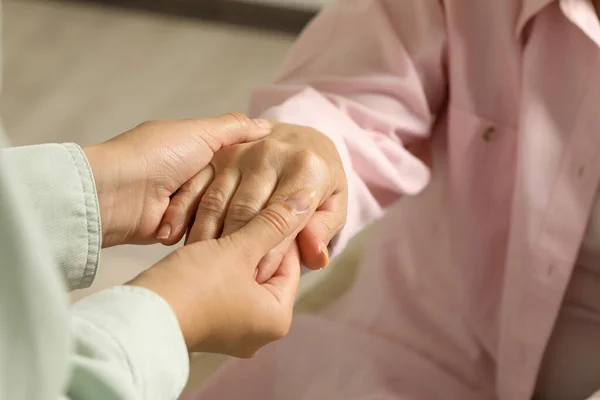 Young Elderly Women Holding Hands Indoors Closeup — ストック写真