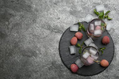 Flat lay composition with delicious lychee cocktails on grey table. Space for text