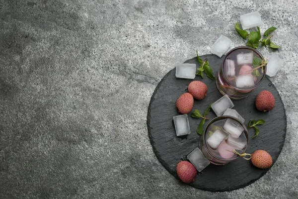Flat lay composition with delicious lychee cocktails on grey table. Space for text