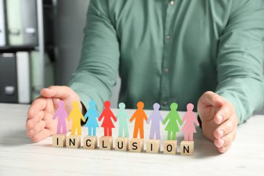 Kağıt insan figürlerini ve tahta küpleri koruyan bir adam. Masada kapalı, yakın plan.