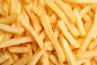 Many delicious French fry pieces as background