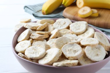 Freeze dried and fresh bananas on white wooden table, closeup
