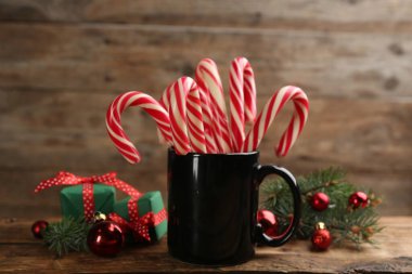 Many sweet candy canes, gift boxes  and Christmas decor on wooden table