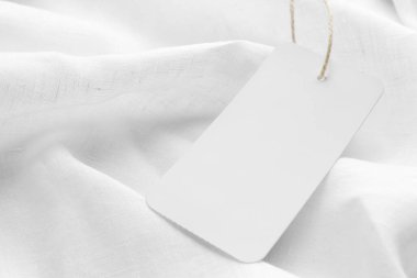 Cardboard tag with space for text on white fabric, closeup