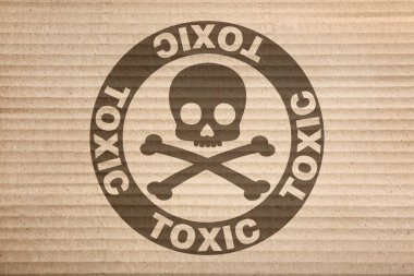 Hazard warning sign (skull-and-crossbones symbol and word TOXIC) on cardboard, top view