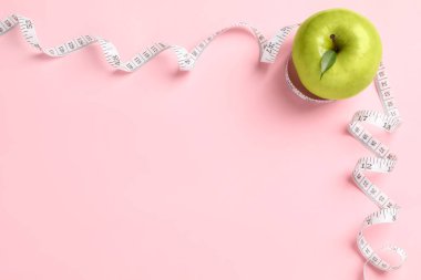 Fresh green apple with measuring tape on pink background, flat lay. Space for text