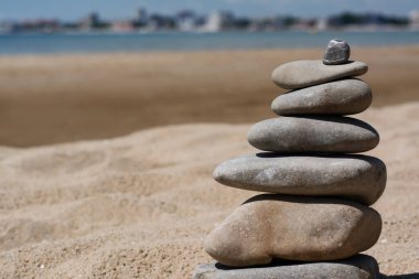 Stack of stones on beautiful sandy beach near sea, closeup. Space for text