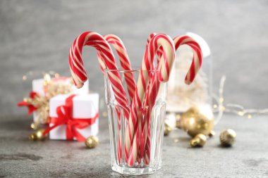 Christmas candy canes in glass on grey table