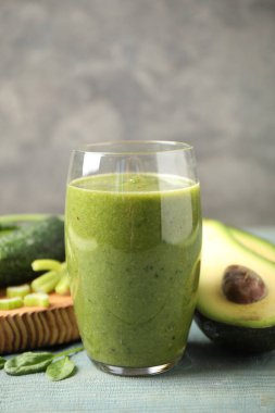 Delicious green juice and fresh ingredients on light blue wooden table