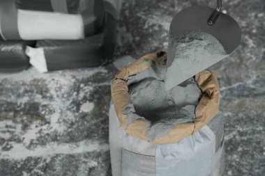 Cement powder and trowel put in bag on stone floor. Space for text