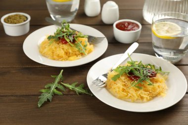 Ahşap masada servis edilen domates soslu ve roka soslu lezzetli spagetti.