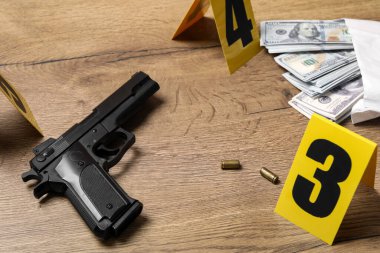 Gun, money and shell casings on wooden background. Crime scene