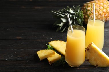 Lezzetli ananas suyu ve siyah ahşap masada taze meyve. Metin için boşluk