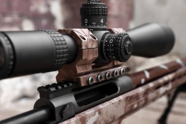 Closeup view of modern powerful sniper rifle with telescopic sight on blurred background