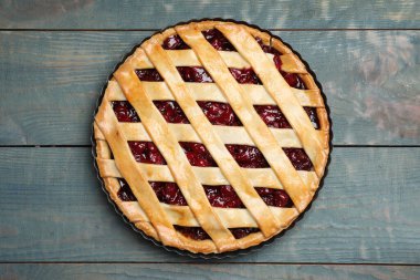 Delicious fresh cherry pie on light blue wooden table, top view