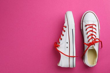 Pembe arka planda bir çift şık spor ayakkabı. Metin için boşluk