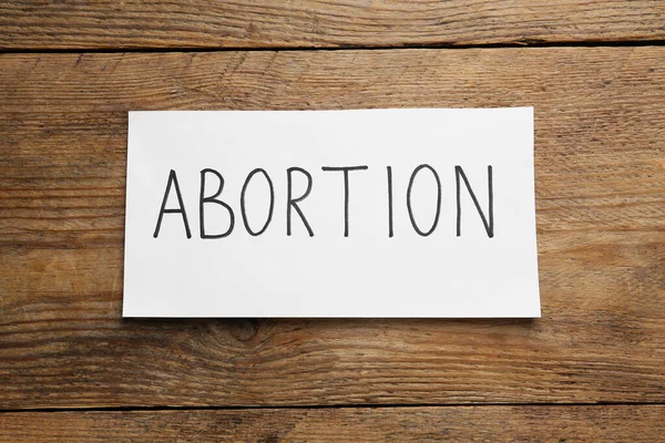 Χαρτί Σημείωμα Λέξη Έκτρωση Ξύλινο Φόντο Πάνω Όψη — Φωτογραφία Αρχείου