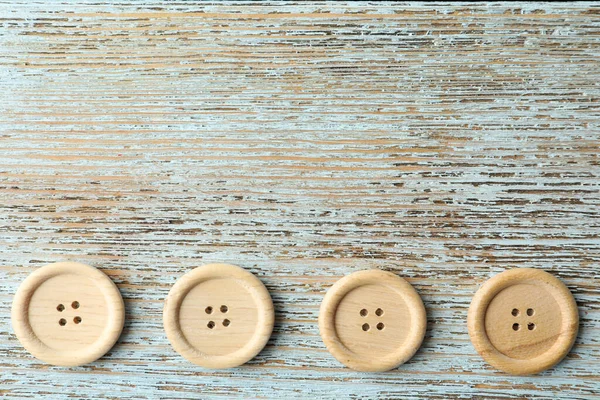 Many sewing buttons on light wooden background, flat lay. Space for text