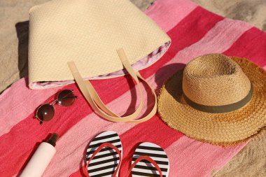 Straw hat, bag and other beach items on sand, closeup